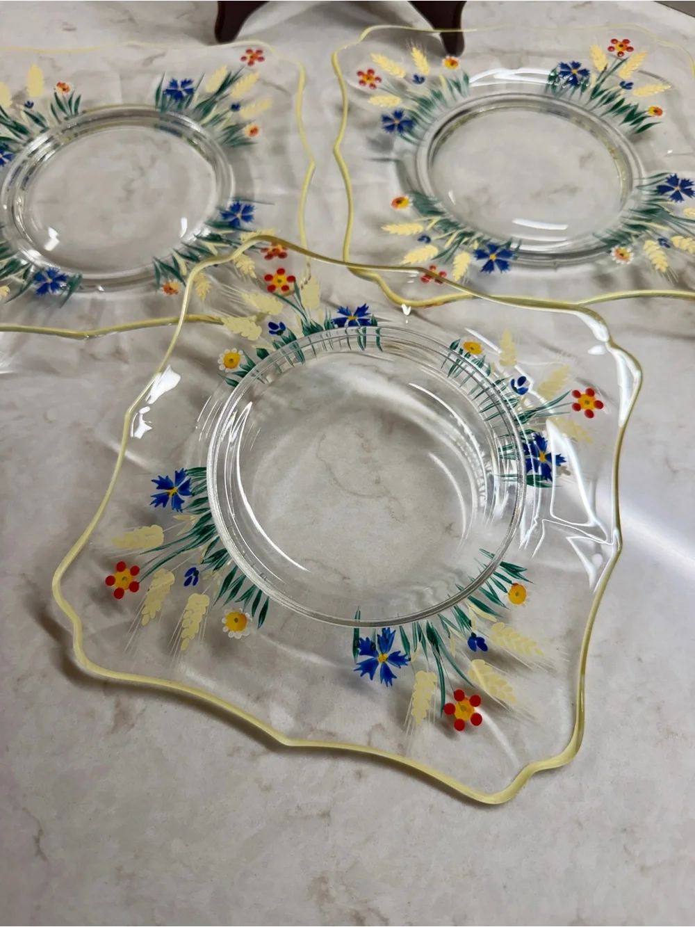 7 1/4” CLEAR GLASS PLATES WITH A COLORFUL, HAND-PAINTED DESIGN & YELLOW TRIM.